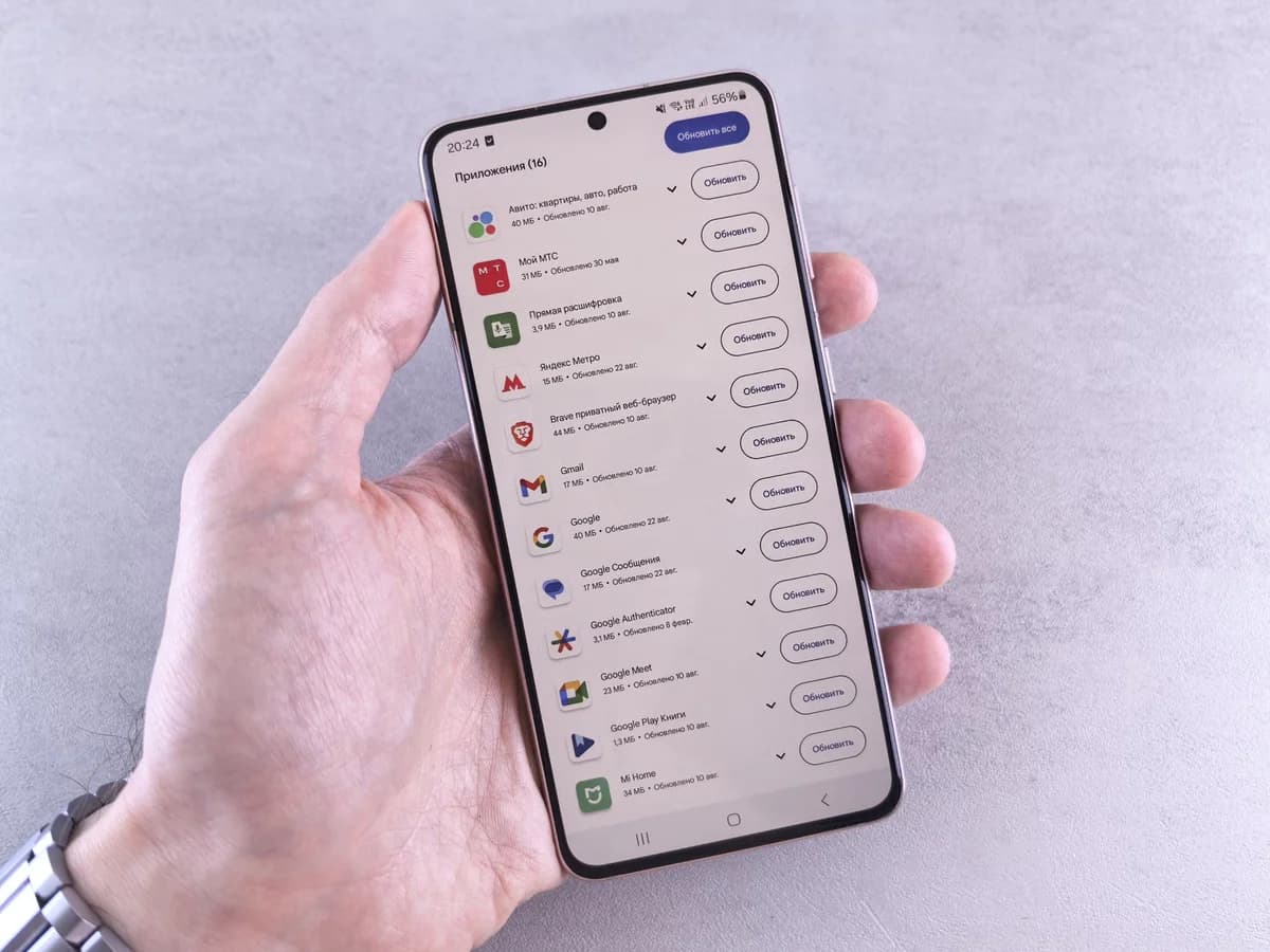 A hand holding a smartphone showing app updates.