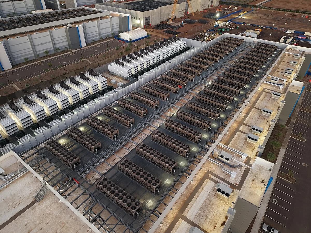 Aerial view of a data center rooftop with rows of cooling towers and backup generators.