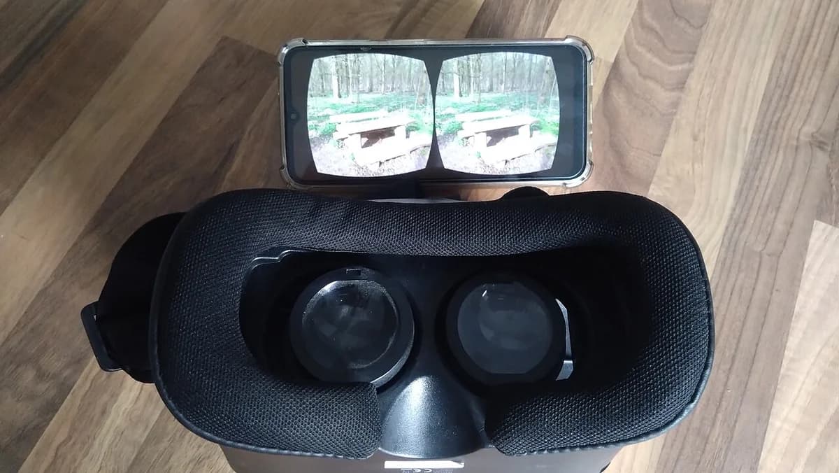 A VR headset with a smartphone on top showing a stereoscopic view.
