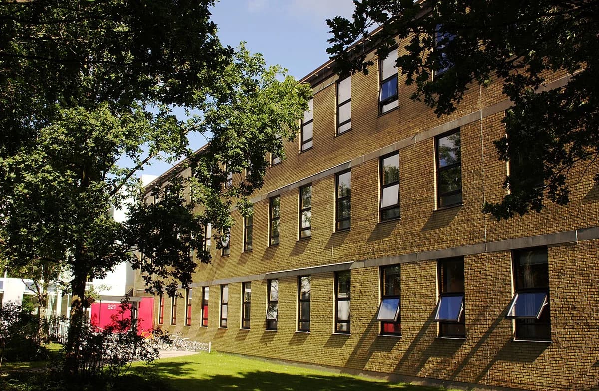 A DTU campus building marked 321, seen through trees, with another building behind it.