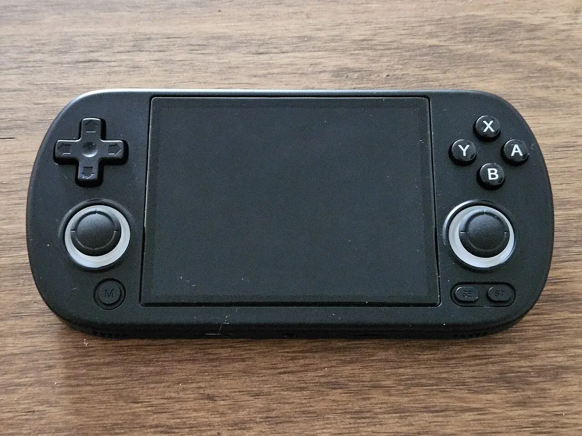 Black handheld retro gaming console on a wooden table.
