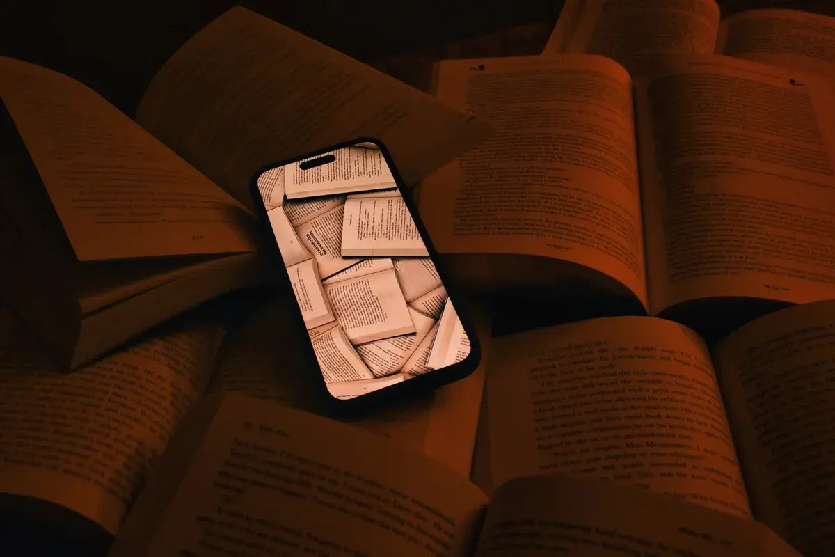 A smartphone lying among open books.