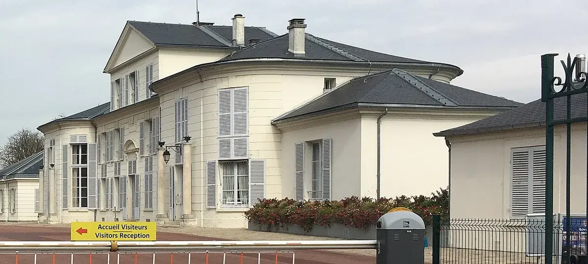 Historic cream-colored building with a visitors reception sign.
