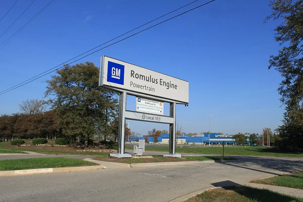 Entrance sign for GM's Romulus Engine Powertrain plant with factory buildings in the background.