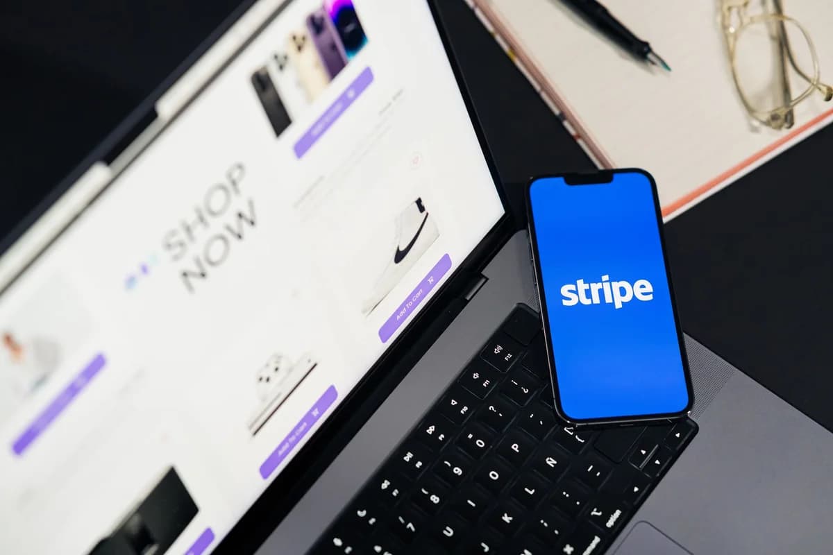 A phone showing the Stripe app next to a laptop with an online shopping page open.