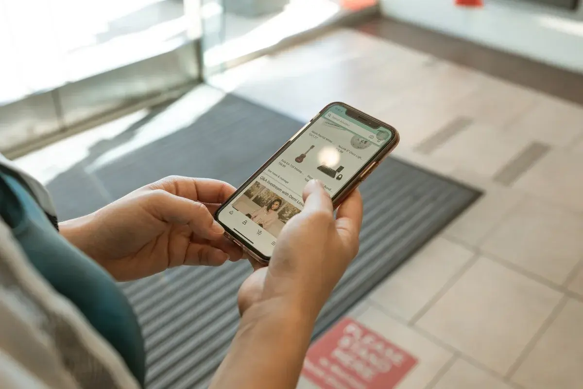 Hands holding a smartphone showing an online shopping app indoors.