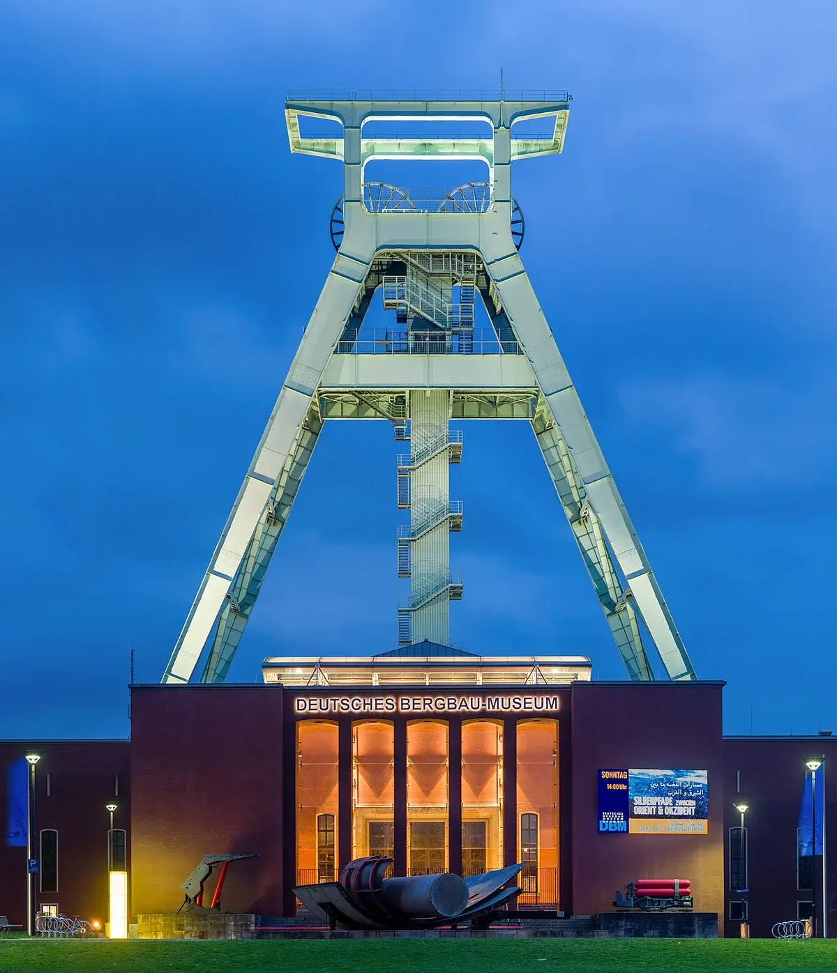 The German Mining Museum in Bochum lit up at dusk beneath a tall mining headframe.