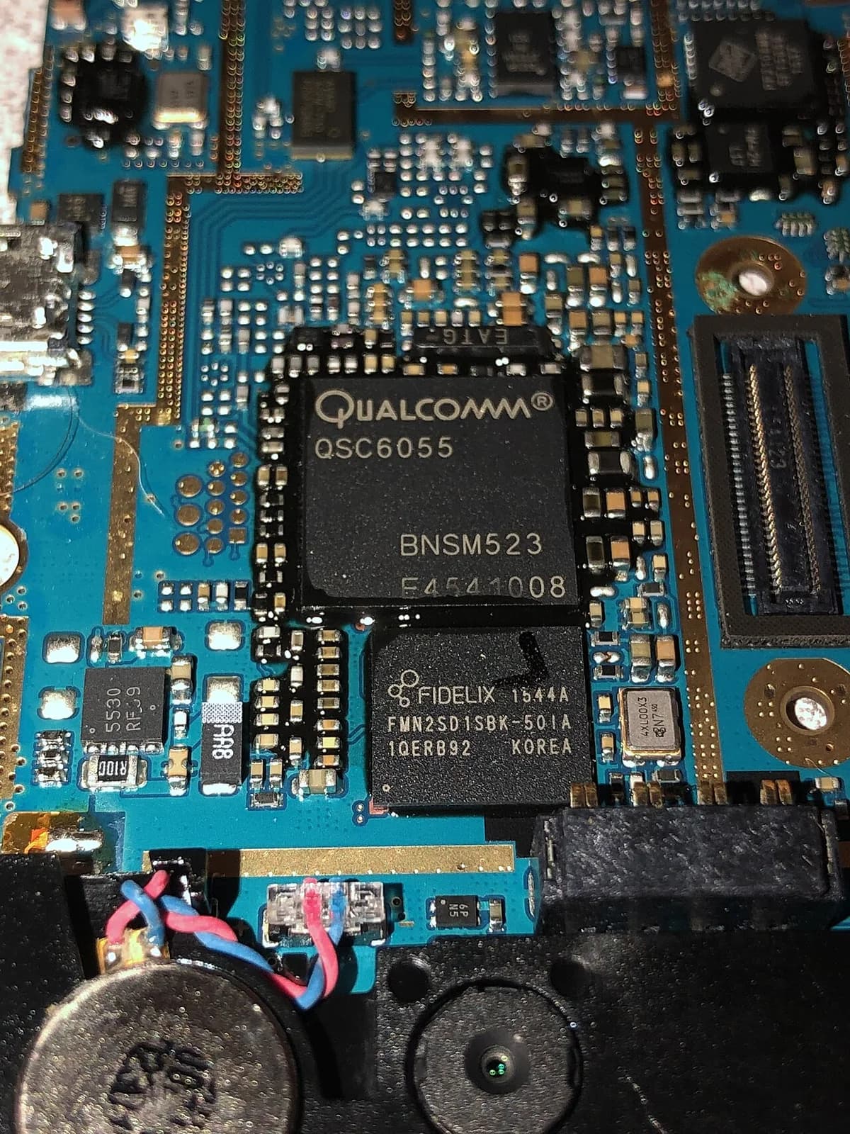 Close-up of a Qualcomm QSC6055 chip on a motherboard with other electronic components.