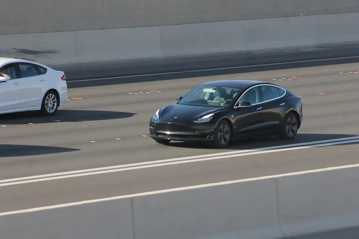 A black Tesla Model 3 driving on a freeway in Las Vegas.