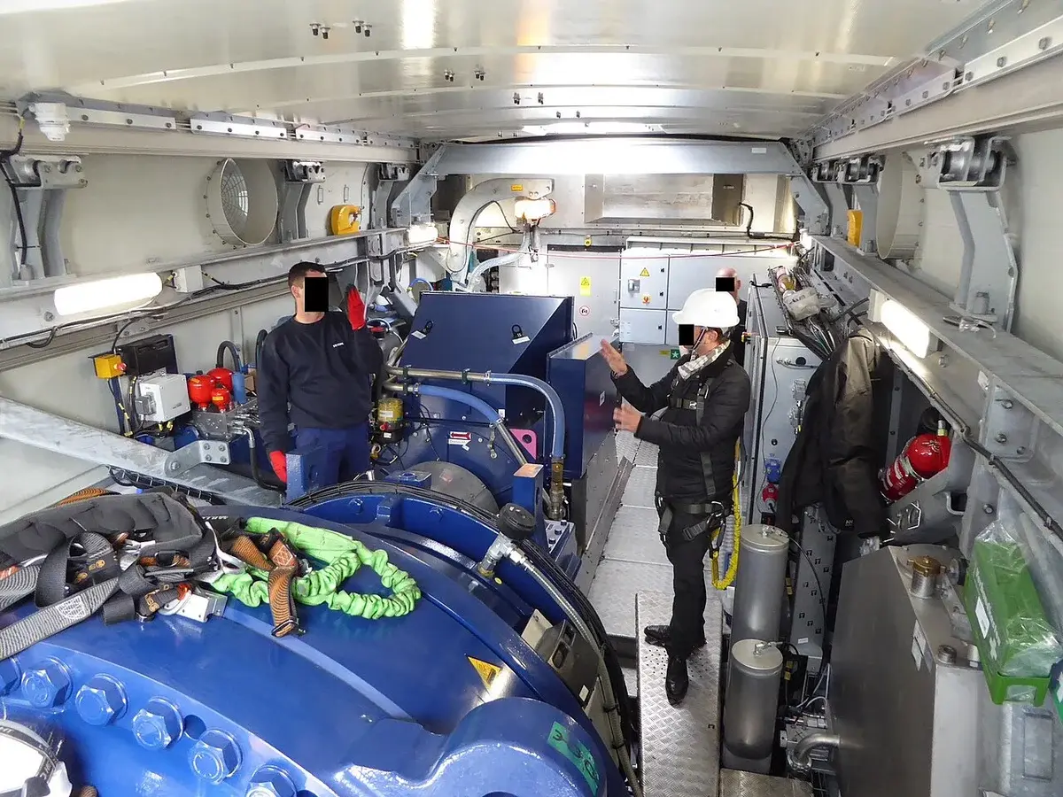 People inspecting the inside of a wind turbine nacelle.