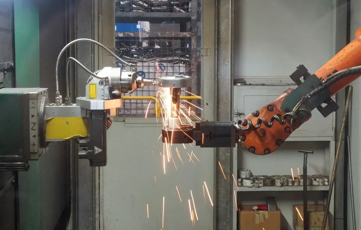 A robotic arm welding metal and throwing sparks in a factory.