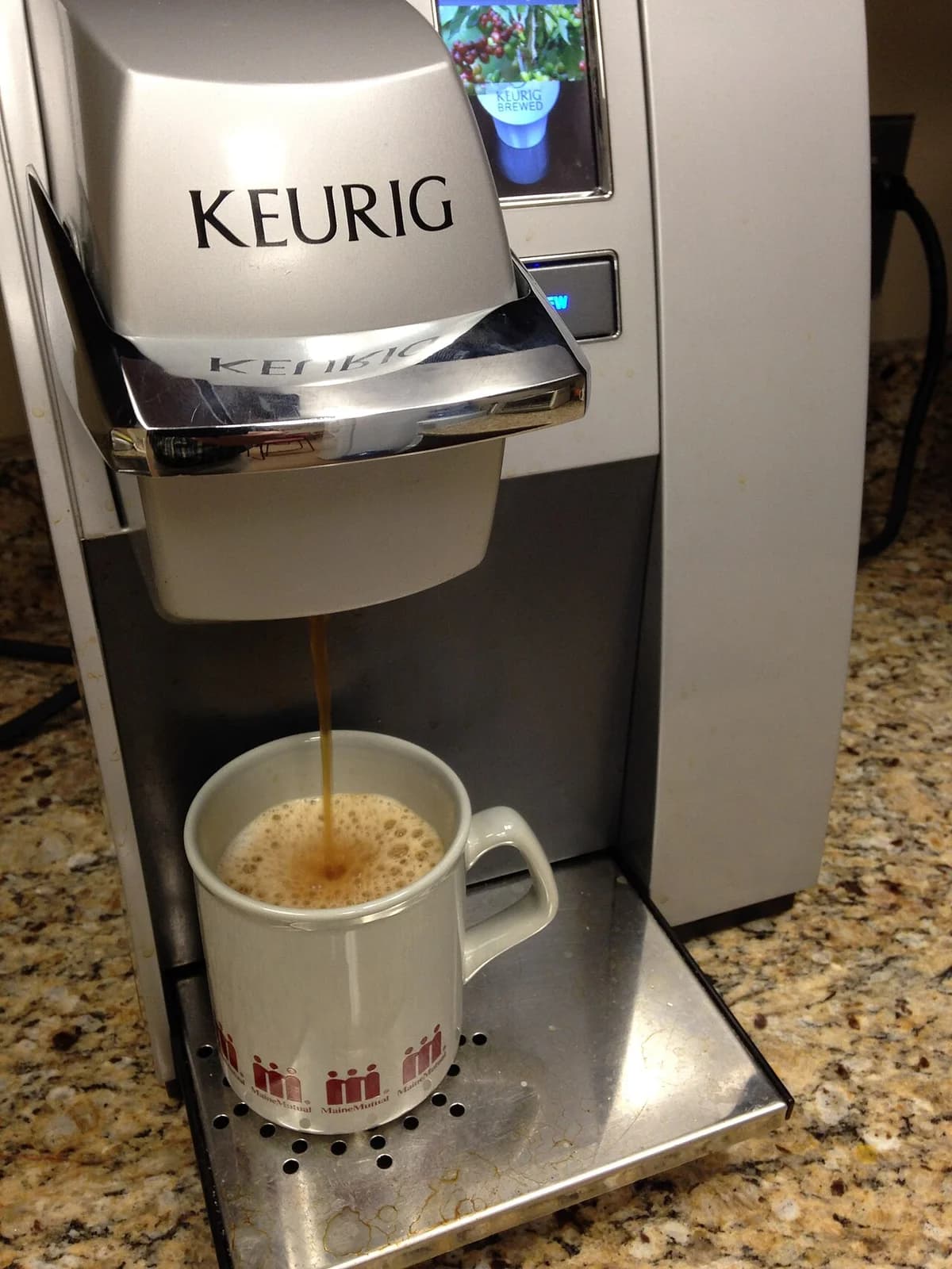 A Keurig coffee maker brewing coffee into a mug.