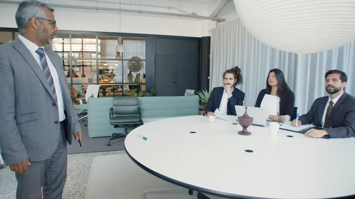 A business meeting in a modern conference room with four professionals around a table.