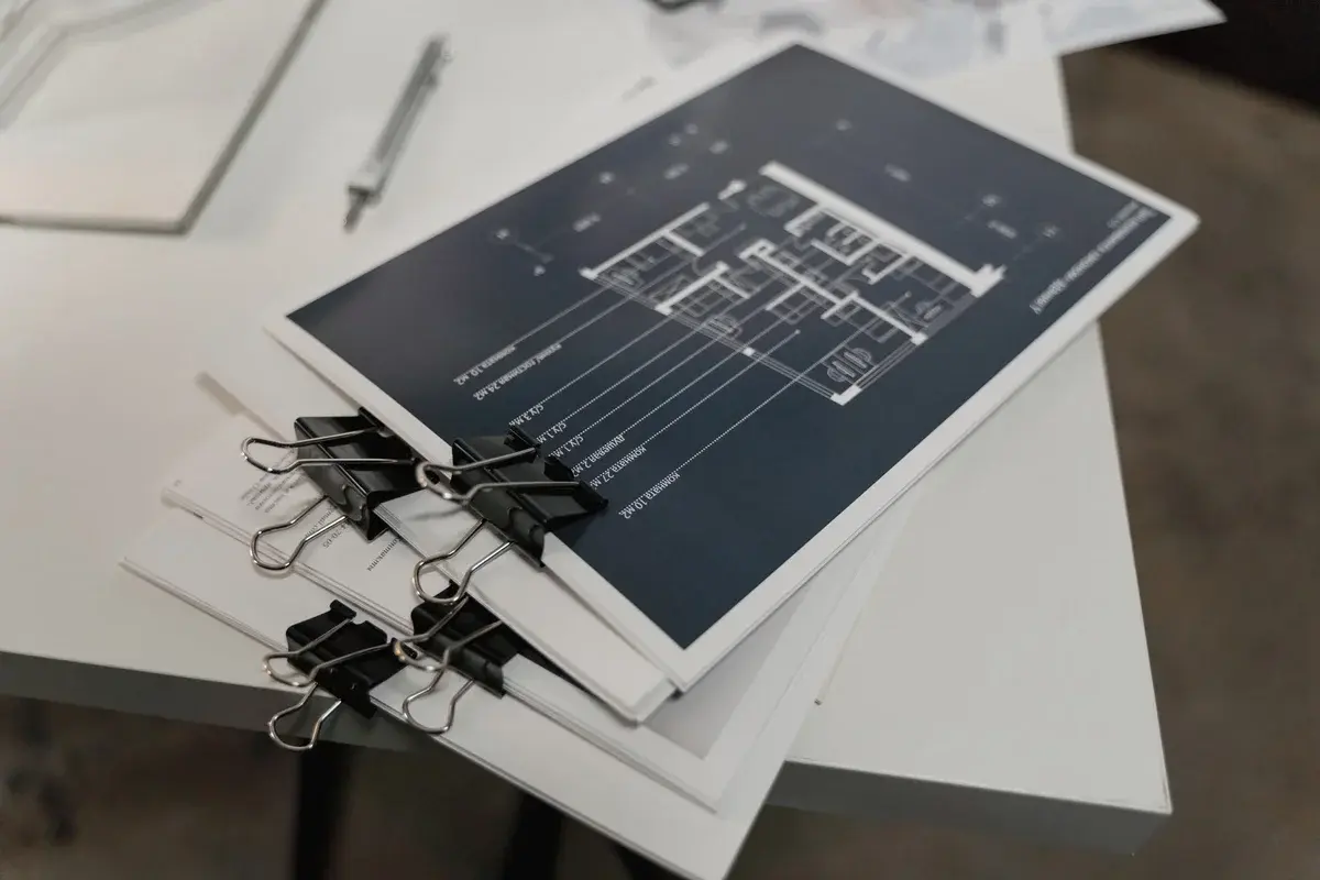 Stack of architectural drawings clipped together on a white table