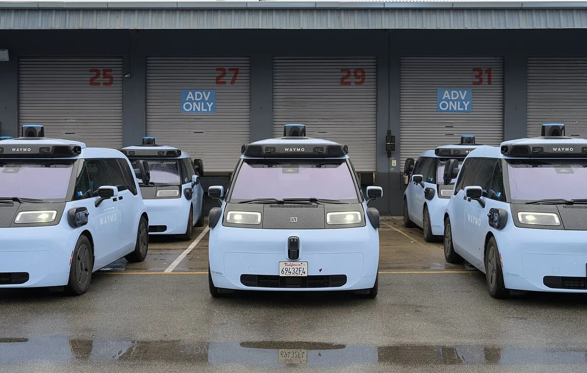 Front view of several Waymo autonomous cars parked at a depot.