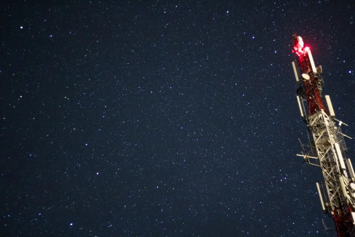 A lit radio tower against a star-filled night sky.
