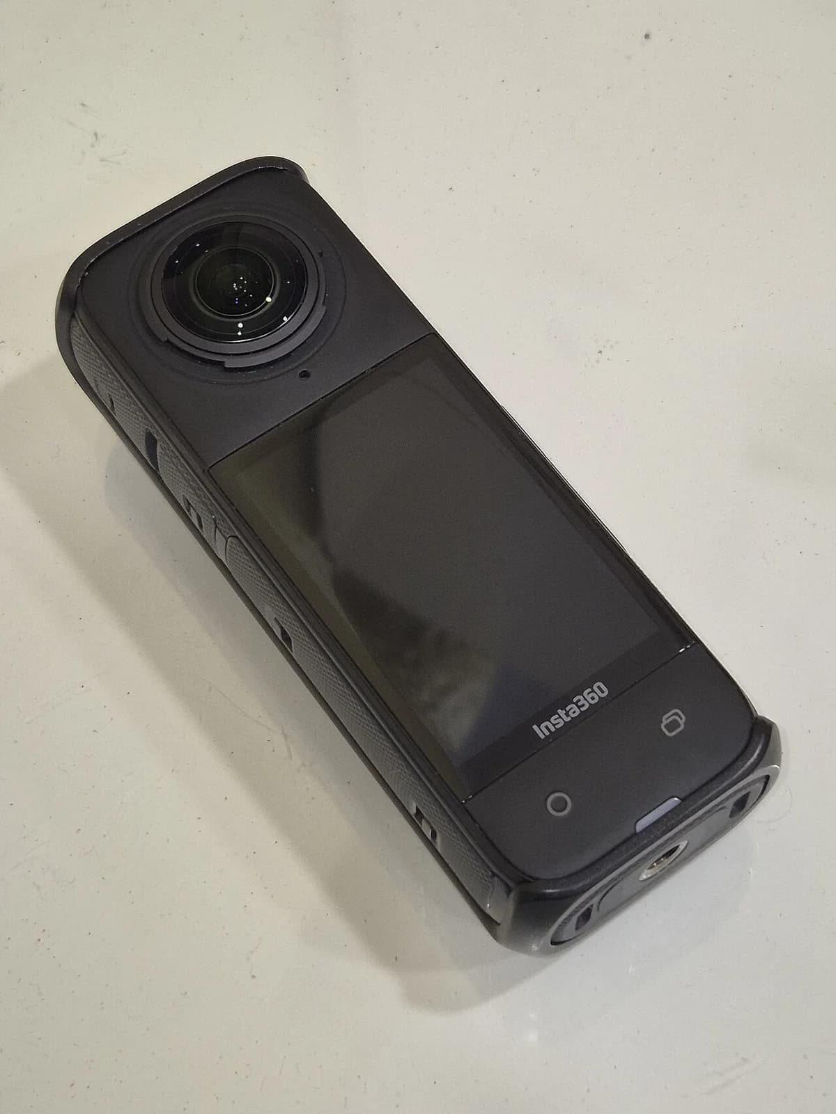 Black Insta360 X4 camera with a thermal cover on a light surface.