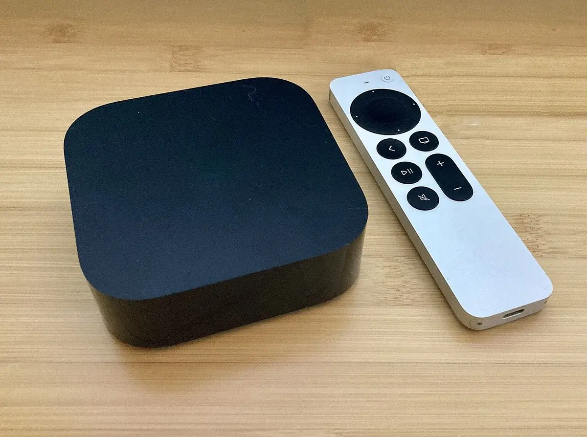 Apple TV 4K box with remote on a wooden table