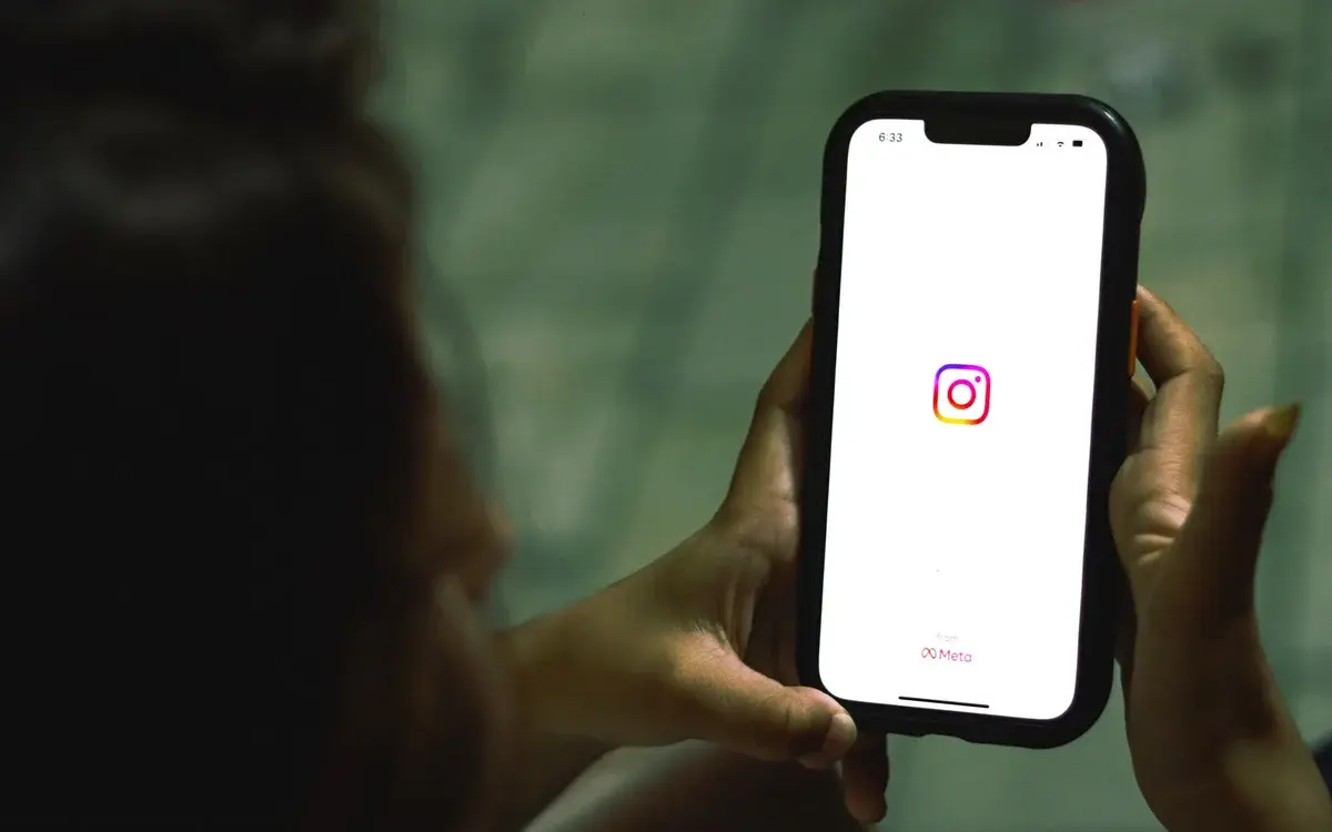 Woman holding a smartphone showing the Instagram app.