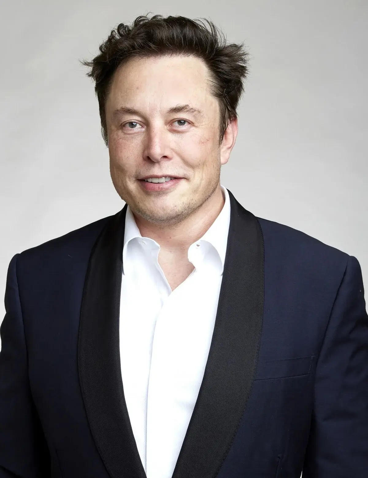 Portrait of Elon Musk in a dark suit and white shirt.