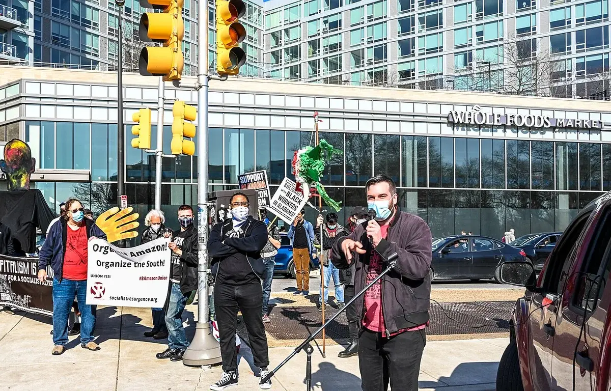 Masked protesters demonstrate outside a Whole Foods Market with signs supporting Amazon workers.
