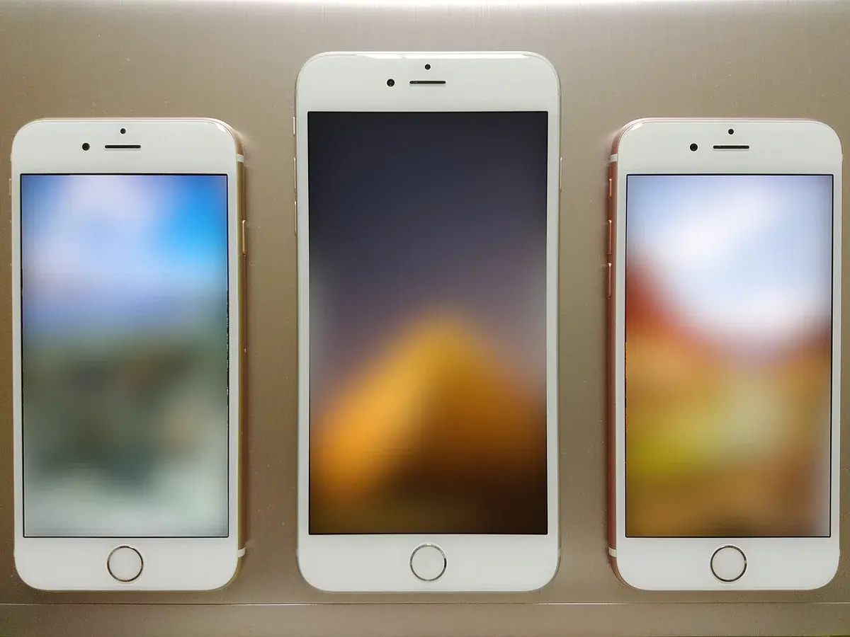 Three iPhones with blurred wallpapers