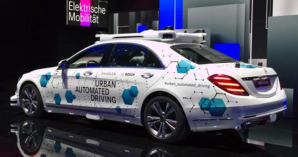 A Mercedes-Benz sedan on display with Urban Automated Driving graphics at an auto show.