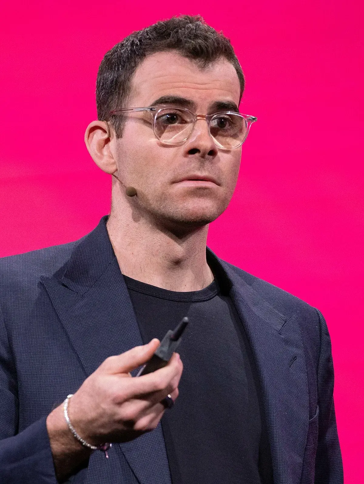 Portrait of Adam Mosseri on stage with a pink background.