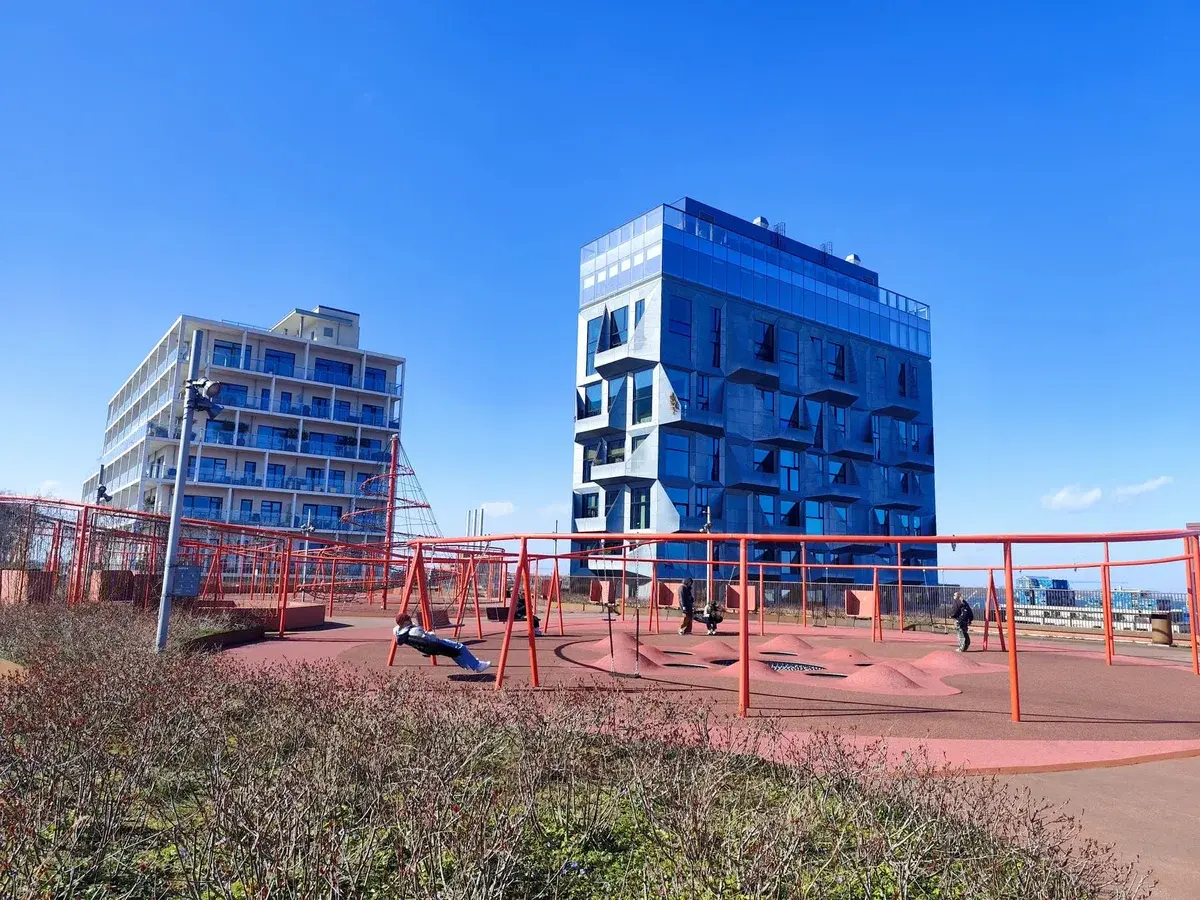 A sunny playground with modern buildings in Copenhagen.