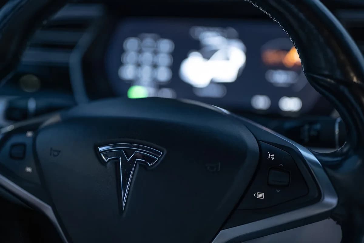Close-up of a Tesla steering wheel with a digital display behind it.