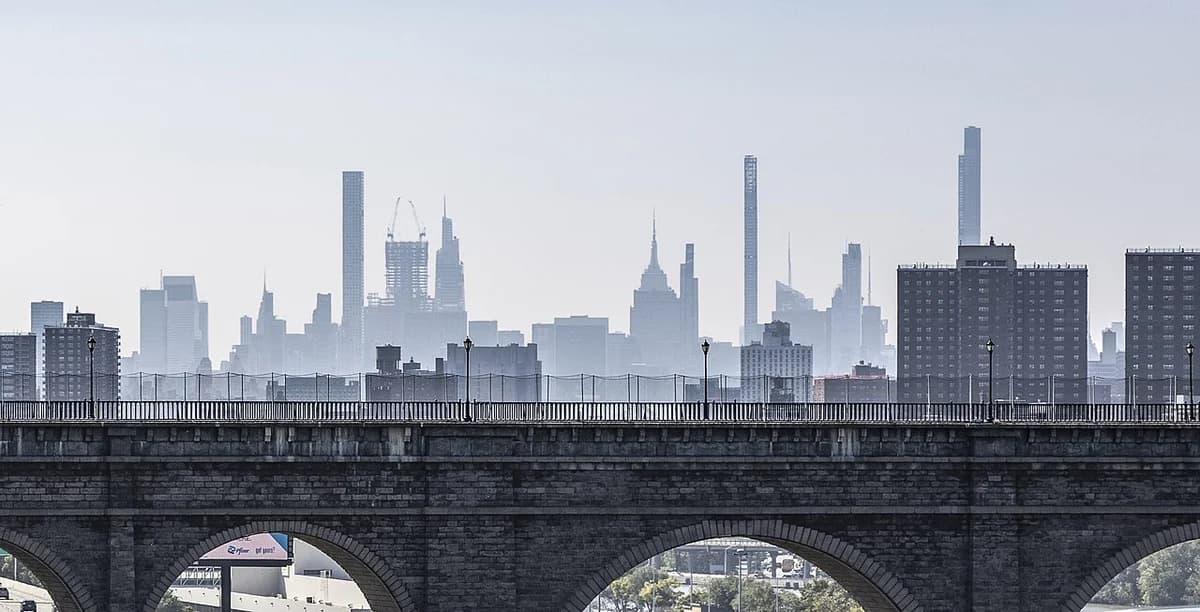 Fog-covered New York City skyline behind a bridge.