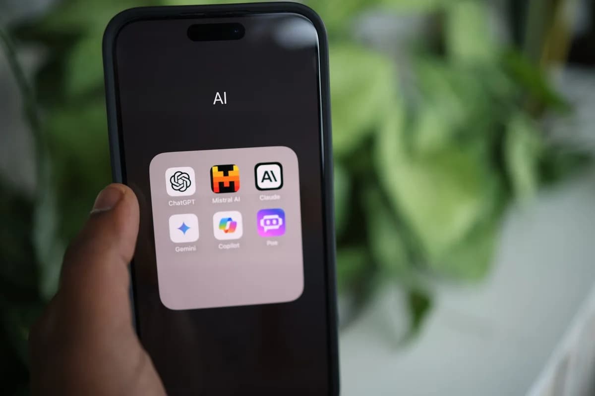 A hand holds a smartphone displaying a folder of AI apps.