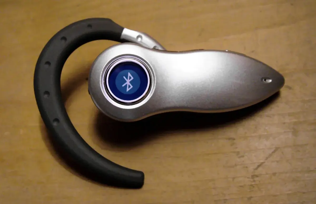 Close-up of a Bluetooth headset on a wooden surface.