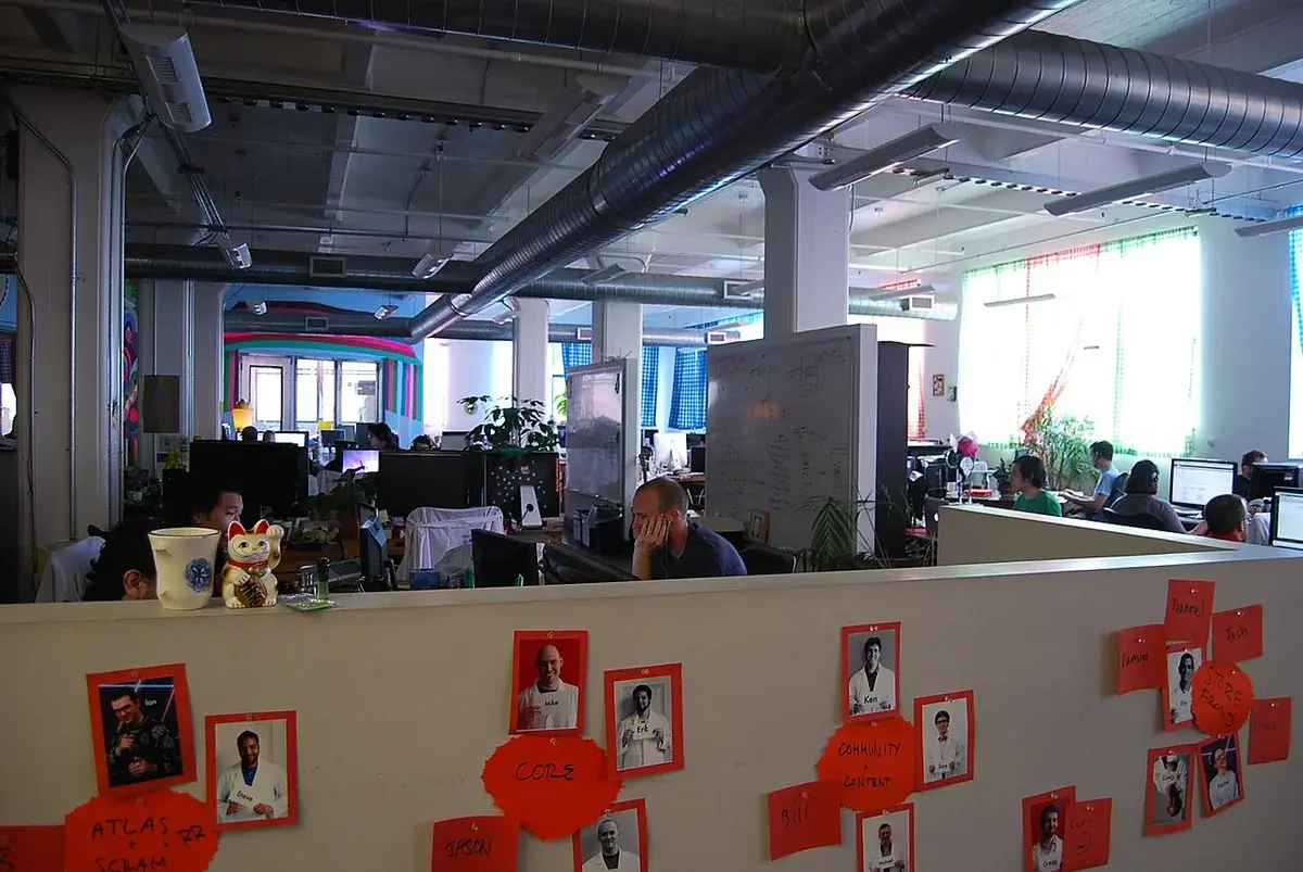People working in an open-plan office with computers and whiteboards.