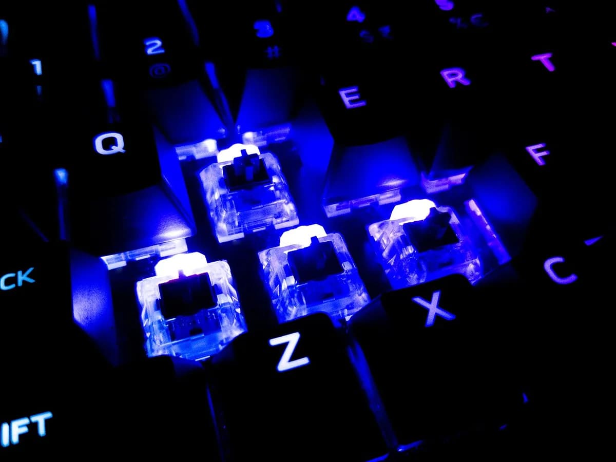 Close-up of a blue-lit mechanical keyboard with transparent switches.