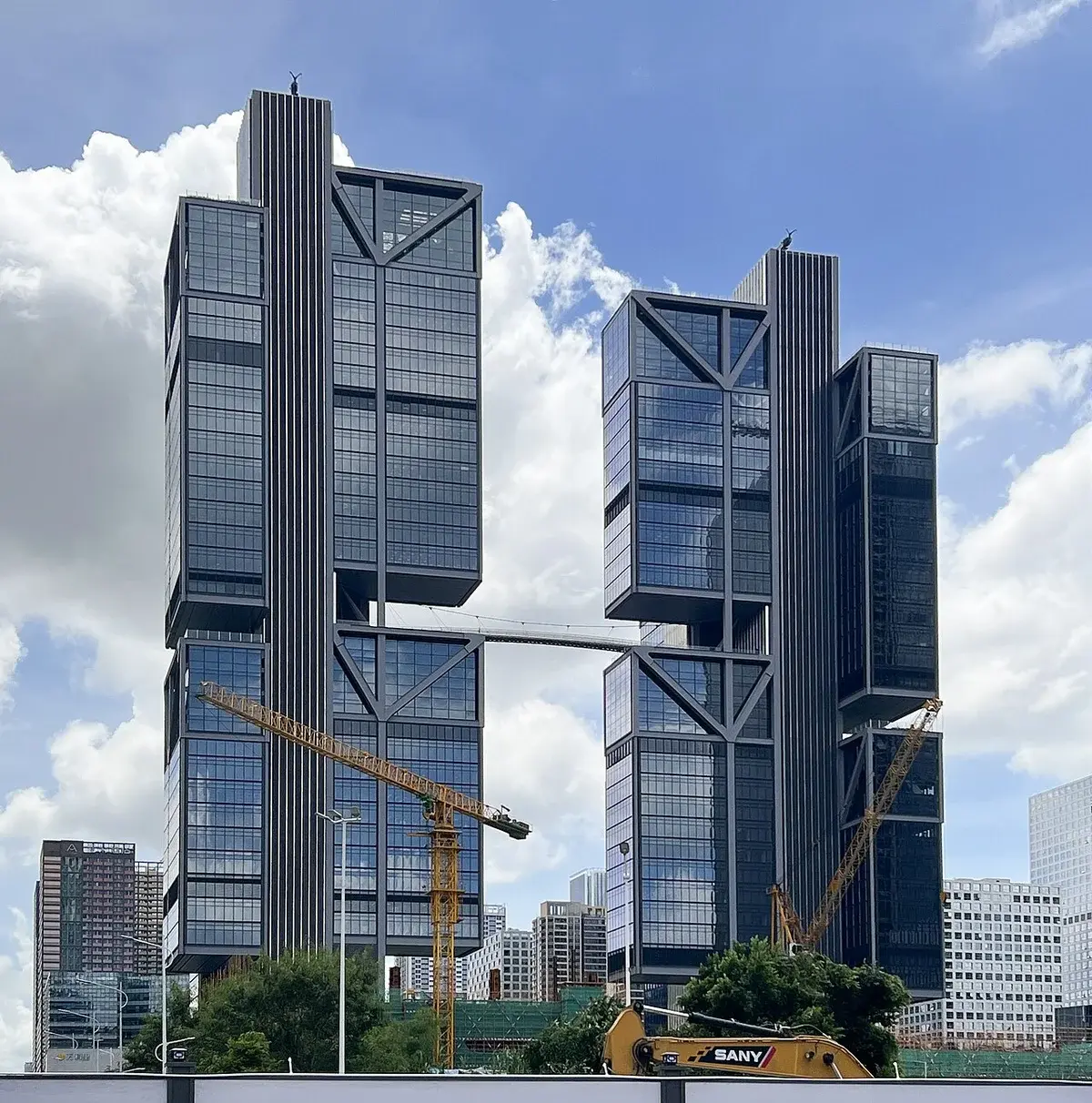 Two modern glass office towers under construction in a city.