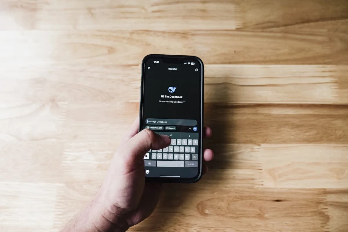 A hand holds a smartphone showing an AI assistant chat screen.